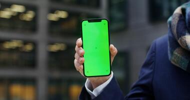 Close-up of a mobile phone with a green screen in the hands of an unknown man. Mockup, copy space, phone screen. in 4k, red komodo video