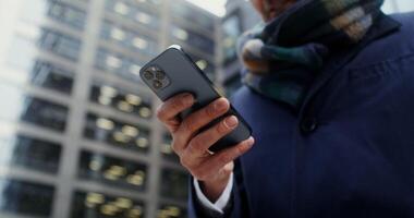 Modern smartphone in the hands of a businessman in a business suit, close-up, unrecognizable person, no face. filming in the open air in the office center of the city. in 4k, red komodo video