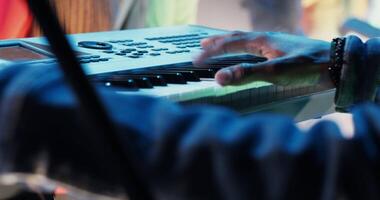 An African-American man plays a synthesizer, shifting levers on the control panel while participating in a concert as part of a musical group, close-up of hands, no face. 4k , red komodo video