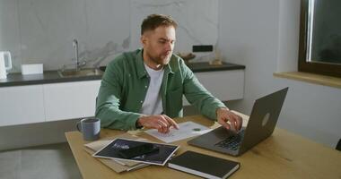 Remote work of an architect under quarantine conditions. A young respectable man of European appearance uses a laptop, setting up a work desk for himself in a stylish kitchen at home video
