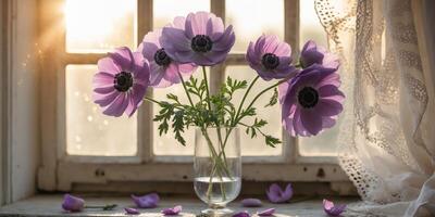 Purple anemone flowers in a glass vase on a windowsill with sunlight streaming in during daytime photo