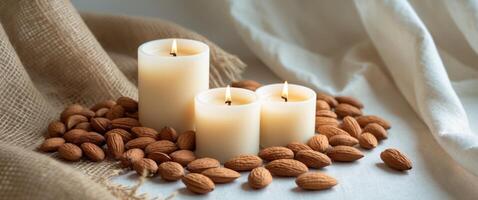 Three lit cream candles on burlap with almonds and nuts create a rustic still life scene photo