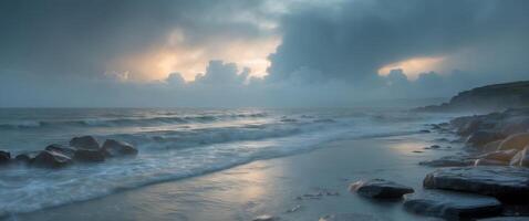 Dramatic dawn over rocky coastline with gentle tide and moody clouds reflecting on tranquil waters photo