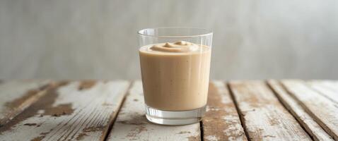 Creamy Beige Smoothie in Glass on Wooden Table photo