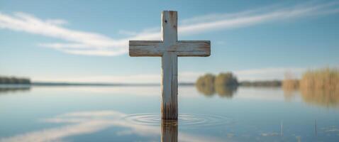 Weathered wooden cross in serene lake under clear blue sky. photo
