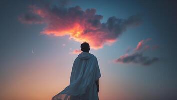A man in a cloak standing on a hill with a cloud in the background photo