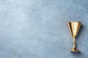 A shiny gold goblet on a textured blue background photo