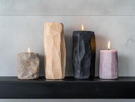 Four candles of different colors and sizes are burning on a black shelf photo
