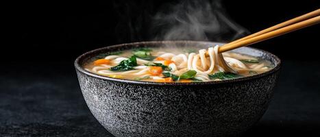 A steaming bowl of noodle soup with vegetables being lifted with chopsticks photo