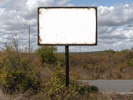 Blank sign on a roadside with cloudy sky background photo