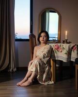 Serene Woman in Floral Dress Sitting by Window at Twilight photo