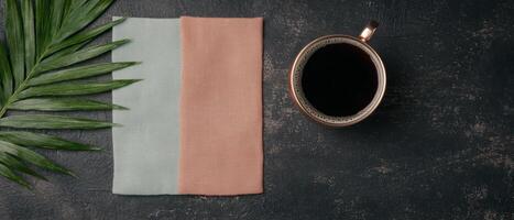 Overhead view of coffee, palm leaf and towels on dark background photo