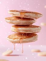 Stack of pancakes with dripping syrup on a pink background photo