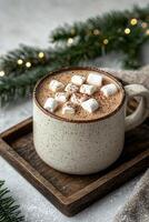 A mug of hot chocolate with marshmallows and a Christmas tree branch in the background photo