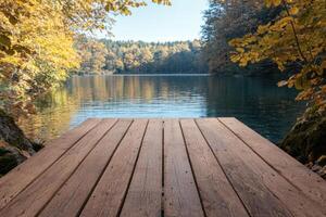 Wooden dock on a tranquil lake surrounded by autumn foliage photo
