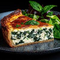 A slice of spinach and cheese quiche with a side salad photo