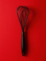 A black whisk on a red background photo