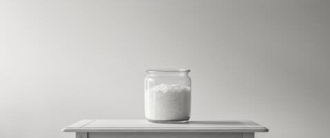 A jar of cream sits on a table with a simple background. photo