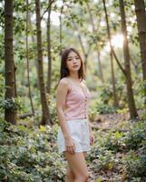 Young woman in casual attire standing in forest setting photo