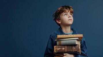 A young boy is holding a stack of books photo