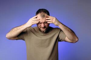 A man has a severe headache. He holds his head in his hands and massages his temples to relieve the pain in his head. Changes in atmospheric pressure affect physical condition and headaches. photo