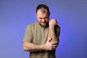 athlete has suffered an elbow injury, causing discomfort. He is holding the affected area, indicating possible tendon or muscle damage. image highlights importance of rehabilitation and prevention. photo