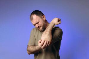 man experiences pain in his elbow due to prolonged sitting at computer. His expression of discomfort indicates a joint problem. It highlights the negative impact of working at a desk without breaks. photo
