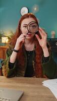 Amazed woman holds magnifying glass near face looking at camera with big zoomed eye analyzing wow video