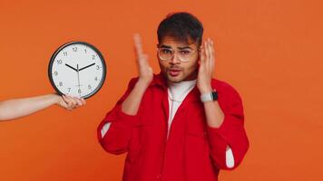 Indian young man with anxiety checking time on clock, running late to work, being in delay, deadline video
