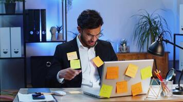 Tired sad exhausted businessman working on laptop at office with many sticker tasks, panic attack video