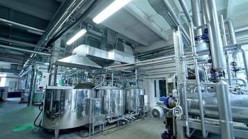 A walk between the shiny silver cisterns at the dairy plant. Modern technologies at producing dairy products. Pipelines and cisterns in the big factory premises. video