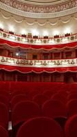 Classical theater inside. Rows of empty red velvet chairs in the opera house. Beautiful dramatic hall with vacant seats. Vertical video
