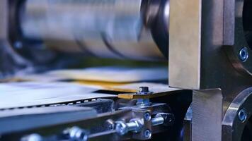 Strong bolts and internal screws holding a construction of a machine for producing diapers. A large rotating horizontal shaft over the conveyer belt blurred at the backdrop.. video