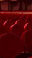 Red chairs background. Rows of comfortable chairs without people in a theatrical hall. Empty auditorium with red velvet seats. Close-up. Vertical video