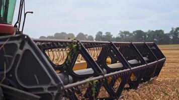 Huge mower mechanism cuts the wheat. Harvesting shears at work. Cloud of dust mixed with grains and straw coming out of massive wheels. video