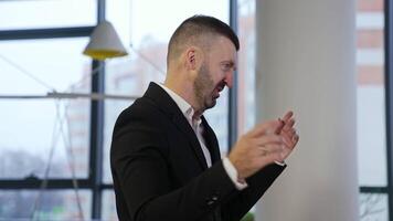 Boss standing with his side and telling something to colleagues. Male in suit explaining work points and gesturing with his hands. Man in a big office. video