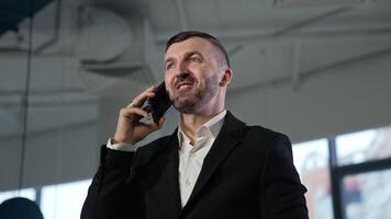 Entrepreneur in suit speaking on the smartphone and smiling. Business phone call and discussing work issues. View from below. video