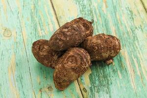 A pile of brown and green coconuts on a wooden table photo