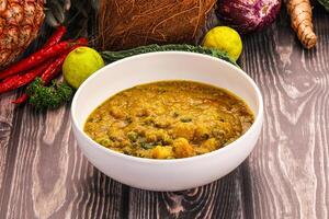 A bowl of soup sitting on a table next to a bunch of vegetables photo