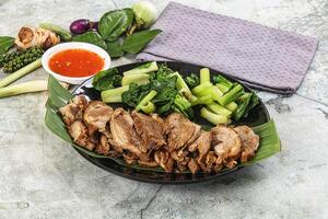 A plate of meat and vegetables with sauce photo