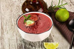 A bowl of red soup with a lime and a spoon photo