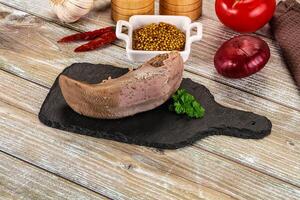 A piece of meat on a cutting board with spices and other ingredients photo