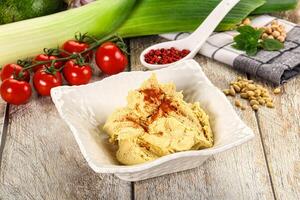A bowl of hummus with vegetables and spices photo