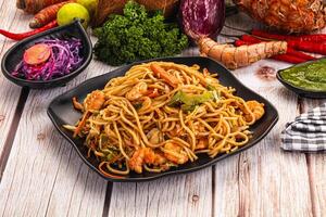 A plate of noodles and vegetables on a table photo