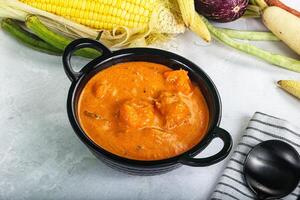 A bowl of soup next to a corn on the cob photo