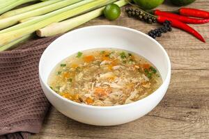 A bowl of soup with vegetables and a towel on a table photo
