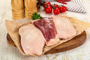 A wooden cutting board with two raw chicken breasts photo