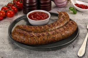 A plate with two sausages and a side of ketchup photo