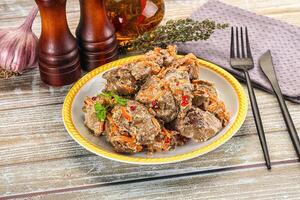 A plate of meatballs with vegetables on a wooden table photo