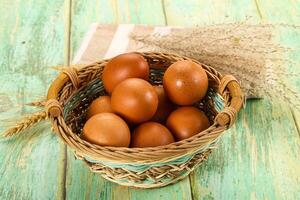 Brown eggs in basket on wooden table photo